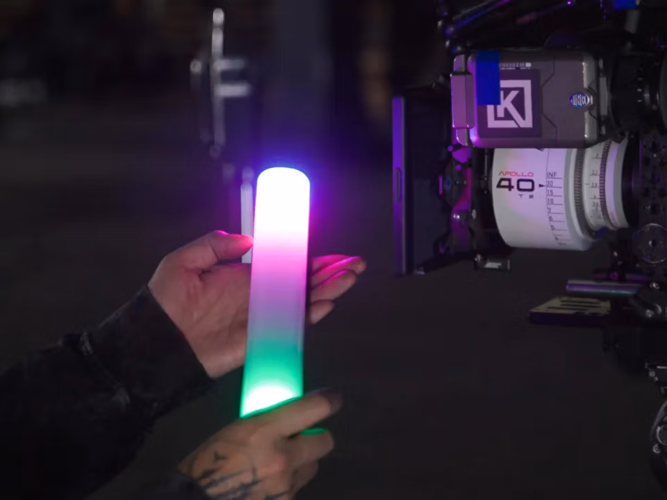 Cвітлодіодна трубка Aputure MT Pro RGBWW Mini LED Tube (APA0202A10) 11 Світильник MT Pro з рожево-зеленим градієнтом кольору біля кінематографічної камери з об'єктивом для демонстрації точного налаштування RGB